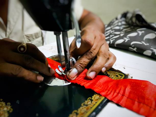 istock Close up photo of manual sewing machine with tailor hands stitching red cloth with selective focus 1163396713