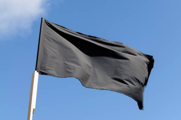 istock Black flag against a blue sky 1163402712