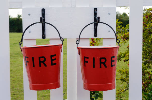 istock Two fire buckets hanging by hooks from a fence 1163402920