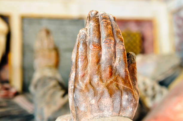 Clasped hands in prayer on a statue on a grave inside an English church