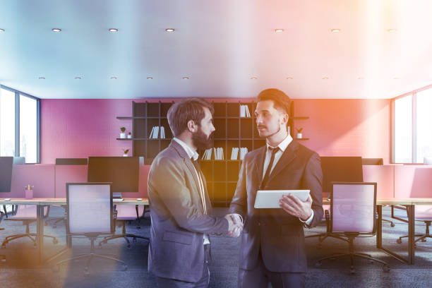 istock Businessmen shaking hands in pink office 1163417056