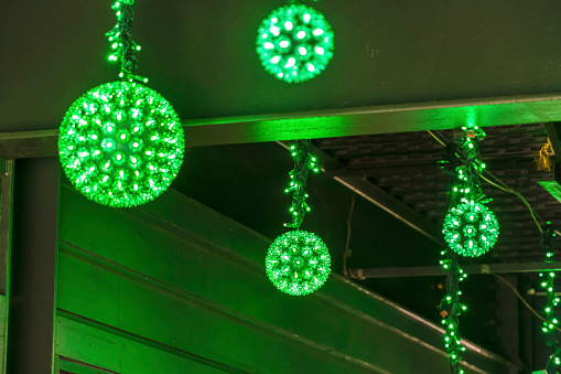 Close up view of several glowing neon green light balls at night. The bright and decorative light balls are hanging on the ceiling of a building.
