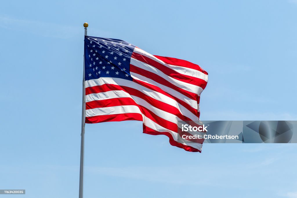 美國國旗在柱子上飄揚,鮮豔的紅色呼嘯和藍色 - 免版稅美國國旗圖庫照片