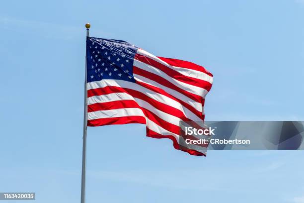 美國國旗在柱子上飄揚鮮豔的紅色呼嘯和藍色 照片檔及更多 美國國旗 照片 - 美國國旗, 美國, 旗幟