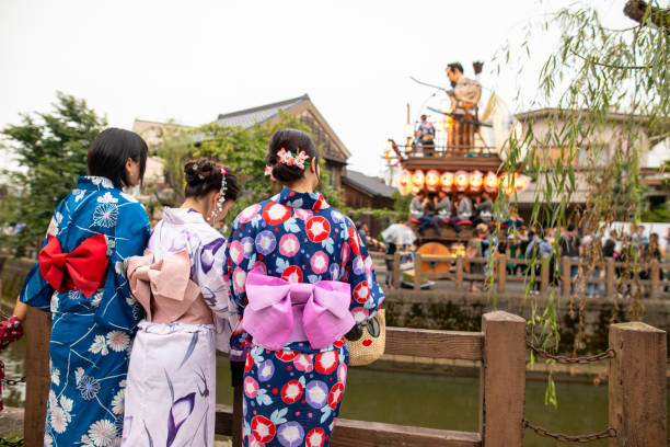 istock Three young women in yukata looking at dashi float at matsuri 1163420974