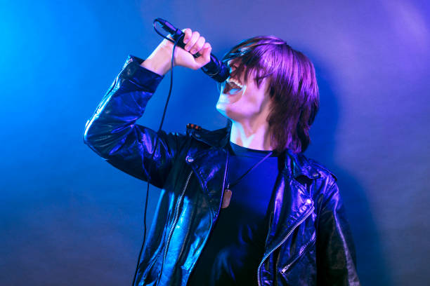 young guy singing rock music The young guy is singing in microphone rock music on the stage, rock concert concept. emo stock pictures, royalty-free photos & images