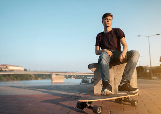 istock Teenager resting on dock with long board 1163422622