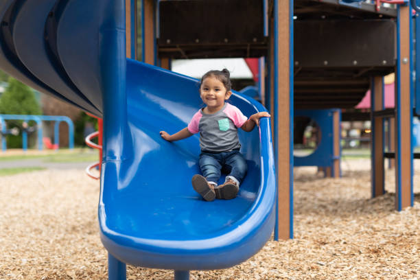 A toddler-age girl riding down the slide