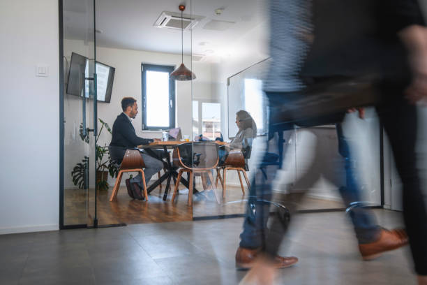 istock Business Colleagues in Motion Past Office Conference Room 1163429559