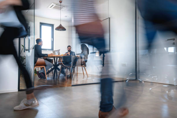 businesspeople in conference room and colleagues walking by - office imagens e fotografias de stock