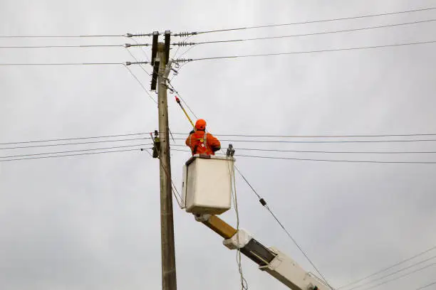 An electrical linesman is hoisted up in a bucket to disconnect power lines while repairs are carried out in Canterbury, New Zealand