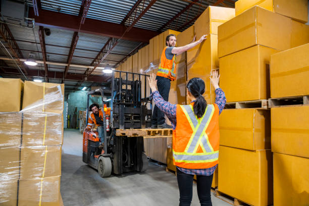 istock An industrial warehouse workplace safety topic. A dangerous situation as a worker is lifted-up by a forklift to reach higher placed merchandise. 1163433995