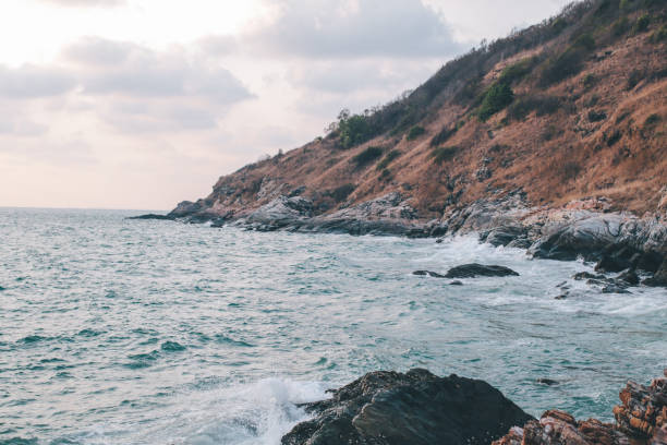 pericolo onda di mare che si schianta sulla costa rocciosa con spray e schiuma al khao laem ya mu ko samet national park rayong, thailandia nel momento del tramonto - flowing nature spray rock foto e immagini stock