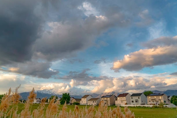 istock Homes amid a vast field with snow capped mountain background under a cloudy sky 1163437555