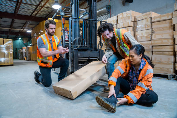An industrial warehouse workplace safety topic. A worker injured falling or being struck by a forklift. stock photo