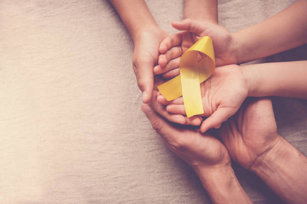 adult and children hands holding yellow gold ribbon, Sarcoma Awareness, Bone cancer, childhood cancer awareness stock photo