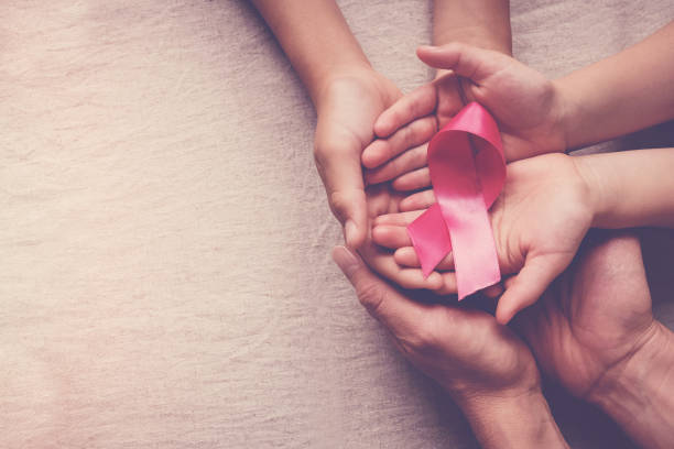 ピンクのリボンを持つ家族の手、乳がんの認識、10月のピンクのコンセプト - world in hands ストックフォトと画像