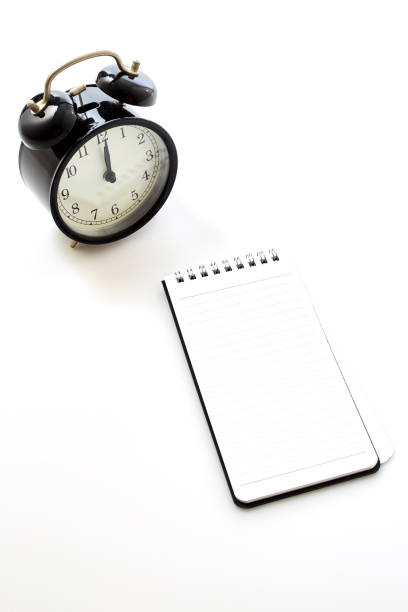 istock Black alarm clock with blank white notebook on white background color 1163448394