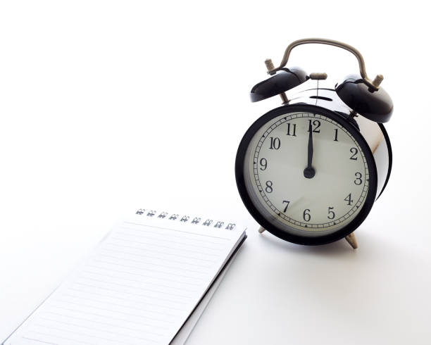 istock Black alarm clock with blank white notebook on white background color 1163448460
