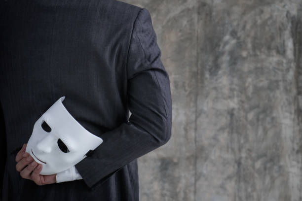 Businessman holding white mask in his hand dishonest cheating agreement.Faking and betray business partnership concept Businessman holding white mask in his hand dishonest cheating agreement.Faking and betray business partnership concept evil stock pictures, royalty-free photos & images