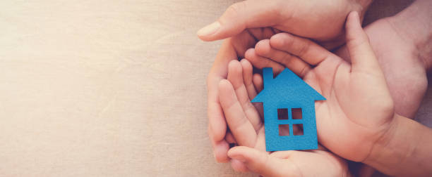 adult and child hands holding blue paper house for family home and homeless shelter concept - take shelter imagens e fotografias de stock