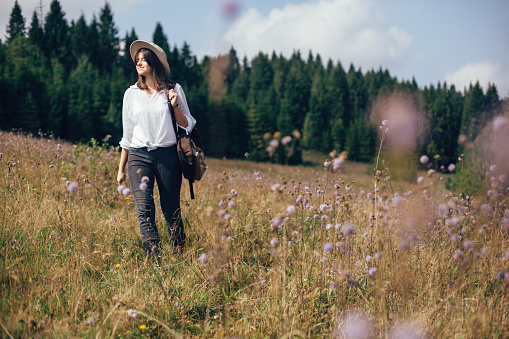 One woman, young female hiker walking on a meadow in sunset.
