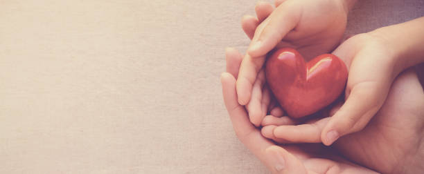 赤い心、心の健康と寄付の概念をホルディング大人と子供の手 - world in hands ストックフォトと画像