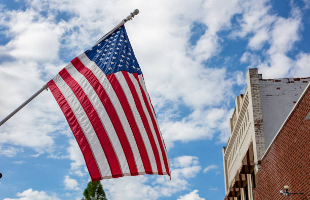 istock United States flag on a pole waving on blue sky background. 1163458827