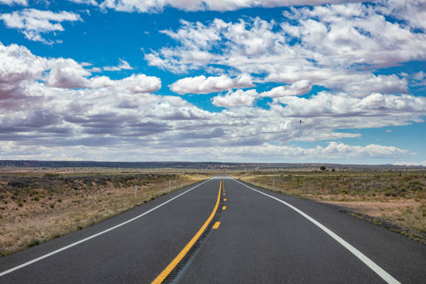 istock Long highway with ups and downs, cloudy blue sky. USA 1163458883