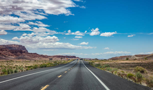 istock Long highway in the american desert, blue cloudy sky background 1163458892