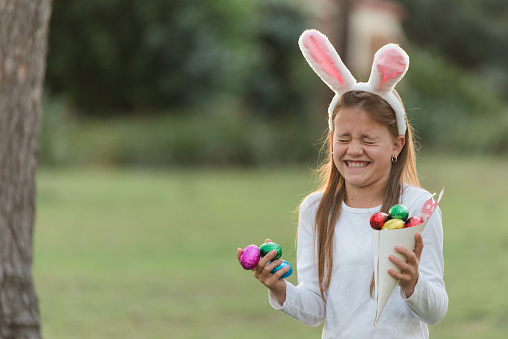 Young girl laughing looking for Easter eggs at Easter egg hunt