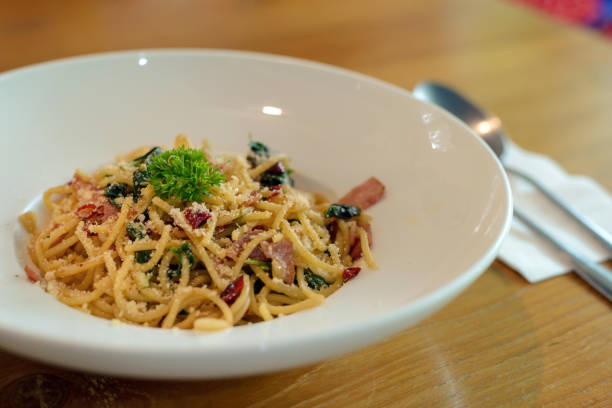 istock Delicious spicy spaghetti with bacon, dried chilli, basil and garlic with fork and spoon prepare side dish 1163461573