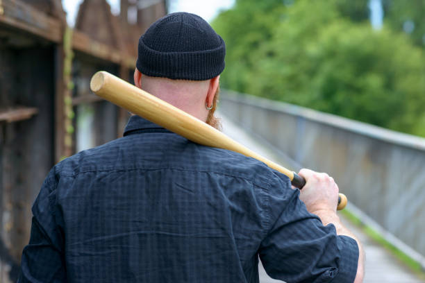 istock Man crossing a bridge with a baseball bat 1163463706