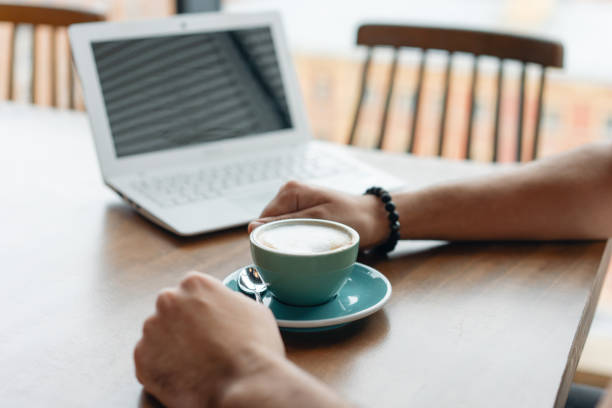 istock Young man drinking coffee from a Cup. Freelancer work on netbook in modern coworking. Programmer at remote job. Successful people, businessman in comfortable cafe. High large Windows 1163467358
