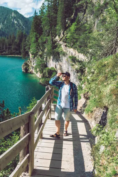 Photo of man walking by hiking trail around braies lake in italy dolomites mountains