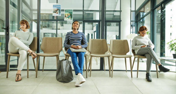 It doesn't feel like a wait with complementary wifi Shot of a group of young women sitting in the waiting room of a clinic waiting room stock pictures, royalty-free photos & images