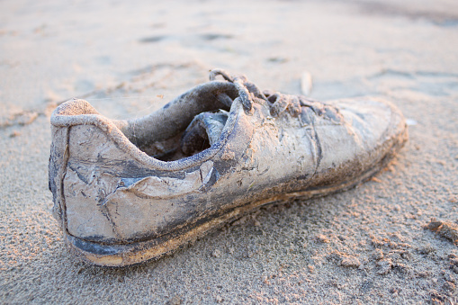 old shoe on the beach. hipster or homeless person shoe