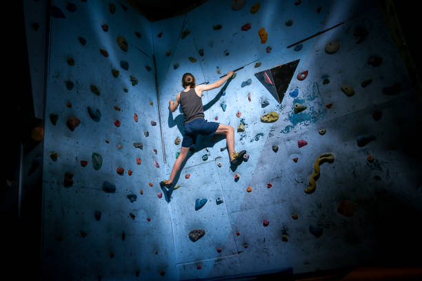 formação do adolescente que escala na parede de escalada interna - climbing wall rock climbing holding reaching - fotografias e filmes do acervo