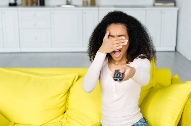 istock african american woman holding remote controller in hand covering face 1163475508