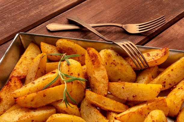 istock Potato wedges, oven roasted with rosemary, in a baking tray on a rustic background 1163478755