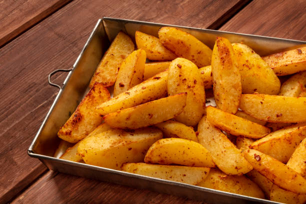 istock Potato wedges, oven roasted, in a baking tray on a rustic background 1163478759