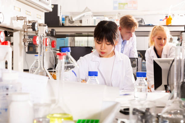 istock Chinese woman lab technician noting results in test chart 1163480609