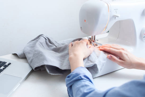 istock Seamstress sitting at desktop with garment equipments and analyzing information from laptop computer 1163483993