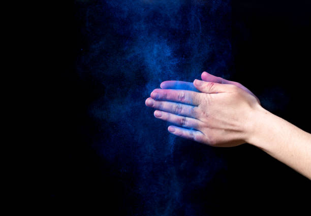 istock Blue powder splatted from woman hands on black background 1163489323