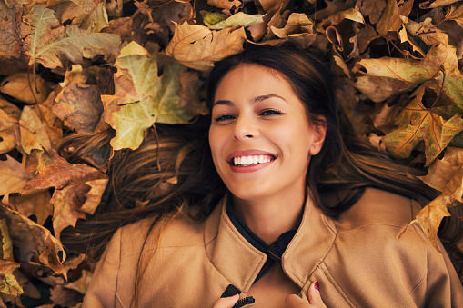 Happy woman lies on the pile of leafs.