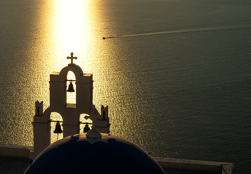close up 3 bells of Fira in sunset silhouette and sunshine on the sea