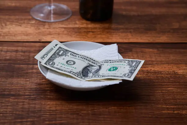 Photo of Restaurant tips or gratuity. Banknotes and coins on a plate