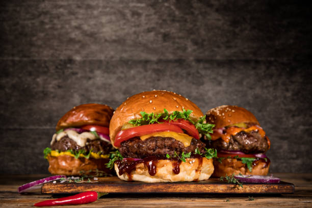 istock Tasty burgers on wooden table. 1163497391
