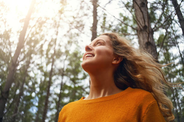 istock Blonde young woman looking up in the forest 1163497430