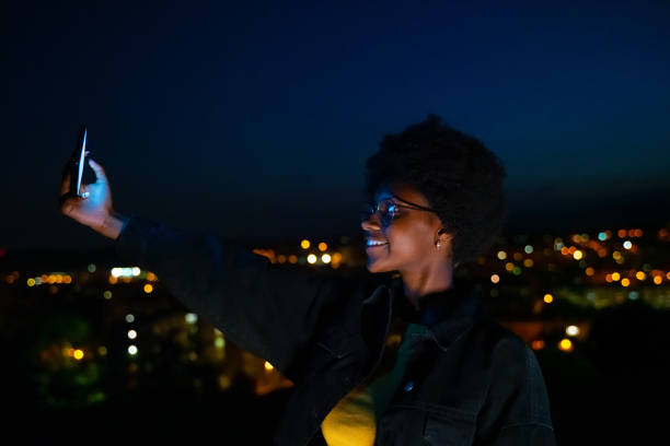 istock Woman taking a selfie with city lights at background 1163499512